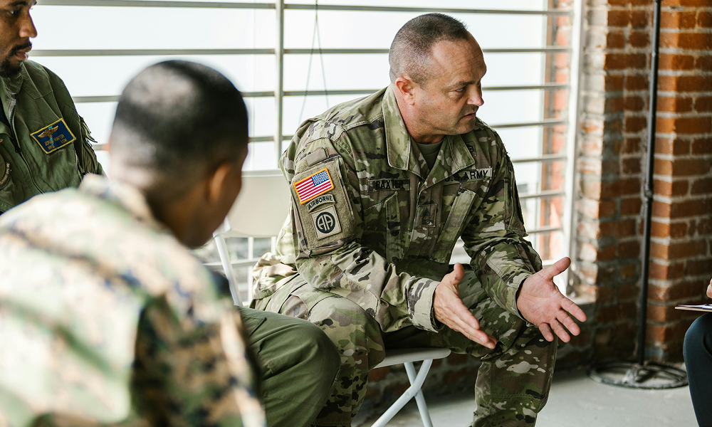 Military personnel engaged in a discussion indoors.